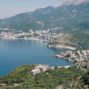 Rugged coast of the Bay of Kotor at the foot of green mountains with resort towns. Montenegro